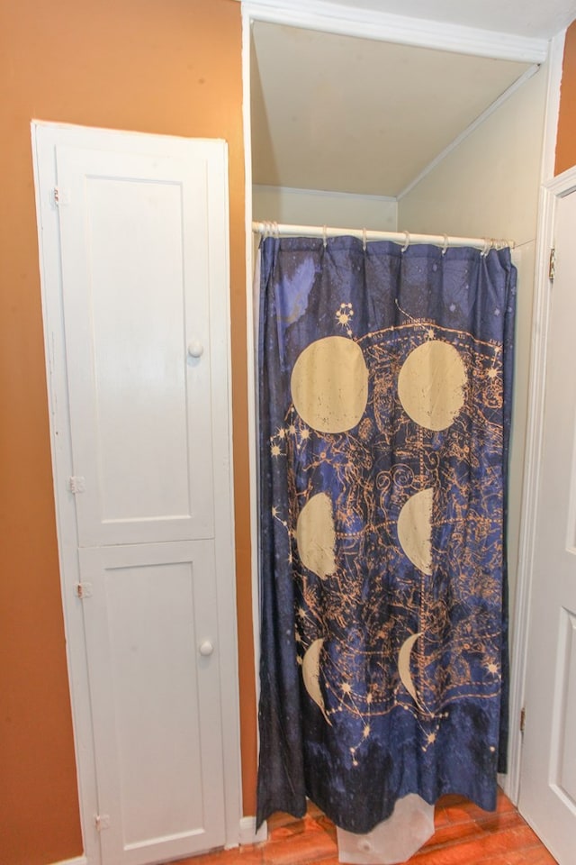 bathroom featuring ornamental molding, curtained shower, and wood finished floors