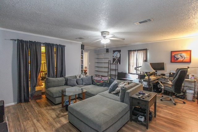 living area with a textured ceiling, ornamental molding, wood finished floors, and visible vents