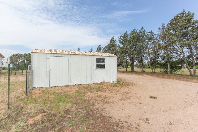view of outbuilding featuring fence and an outbuilding