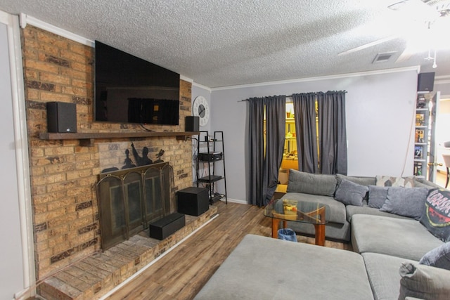 living area featuring crown molding, a textured ceiling, wood finished floors, and visible vents