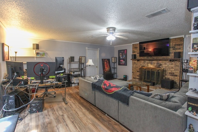 living area with visible vents, a ceiling fan, a textured ceiling, and wood finished floors