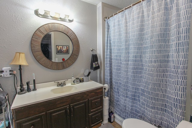 bathroom featuring vanity, a textured wall, curtained shower, and toilet