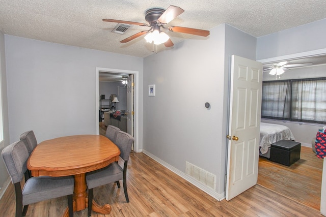 dining room featuring a ceiling fan, baseboards, visible vents, and light wood-style floors