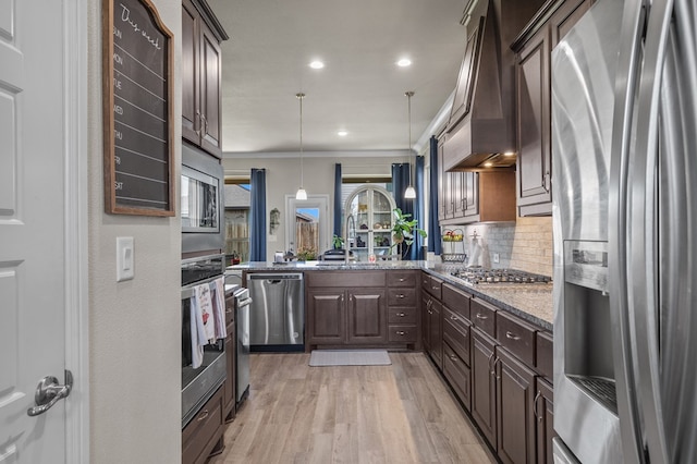 8421 E County Rd 115, Midland, TX 79706 - kitchen featuring appliances with stainless steel finishes, dark brown cabinets, crown molding, dark stone counters, and light wood-style flooring