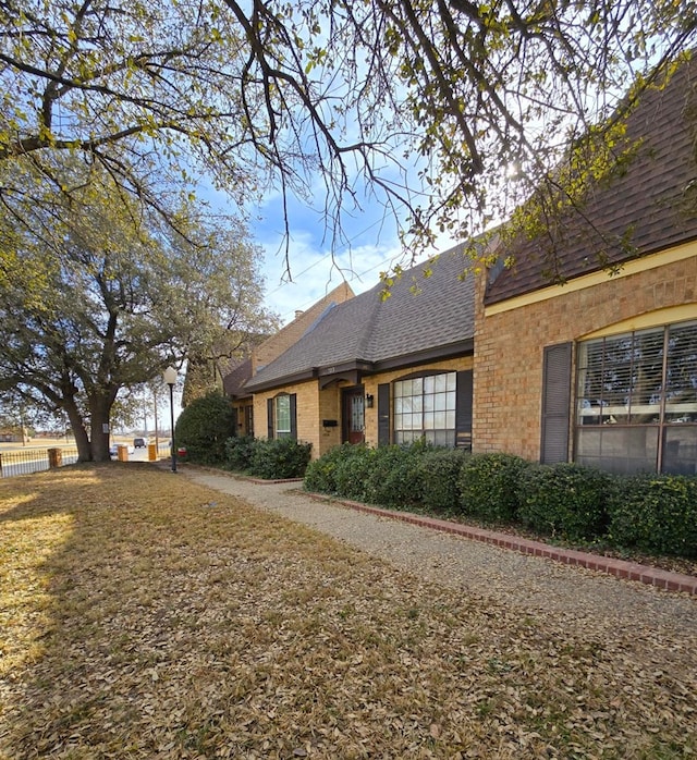 view of front of property with brick siding and a shingled roof