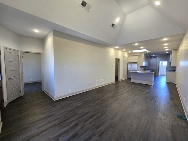 unfurnished living room with high vaulted ceiling, dark wood-style flooring, visible vents, and baseboards