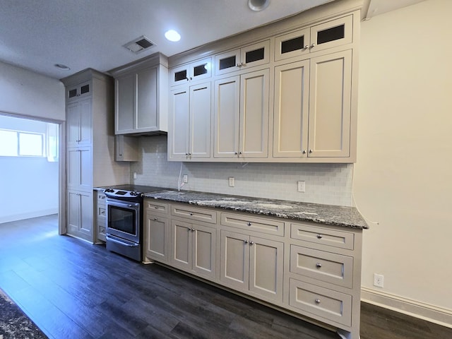 kitchen with electric stove, dark wood finished floors, tasteful backsplash, glass insert cabinets, and stone countertops