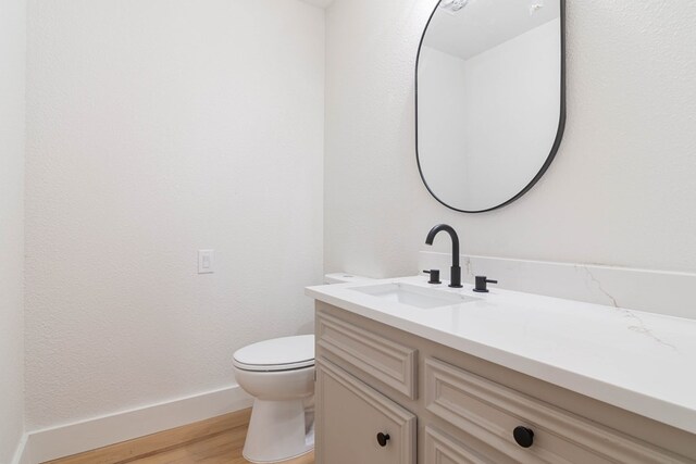 1017 Ward St, Midland, TX 79701 - bathroom with vanity, toilet, wood finished floors, and baseboards