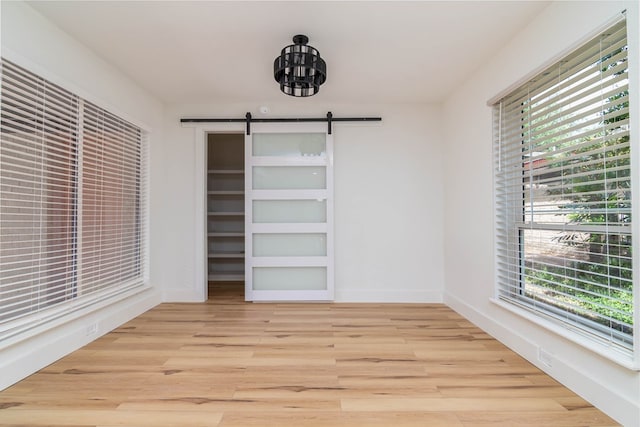 1017 Ward St, Midland, TX 79701 - unfurnished dining area featuring light wood-style floors, a barn door, baseboards, and a chandelier