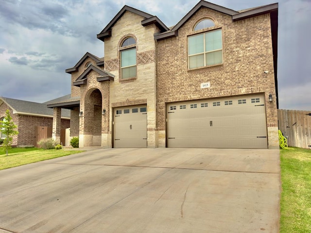 view of front of home with a garage, fence, driveway, and brick siding