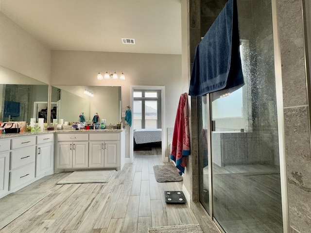 bathroom featuring a walk in shower, vanity, wood finished floors, ensuite bathroom, and visible vents