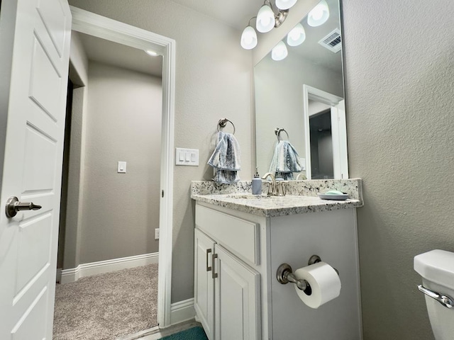 half bathroom featuring toilet, baseboards, visible vents, and vanity