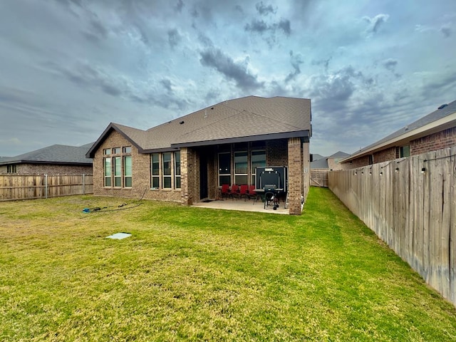 back of property featuring brick siding, a fenced backyard, a patio area, and a yard