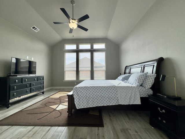 bedroom with baseboards, vaulted ceiling, wood finished floors, and visible vents