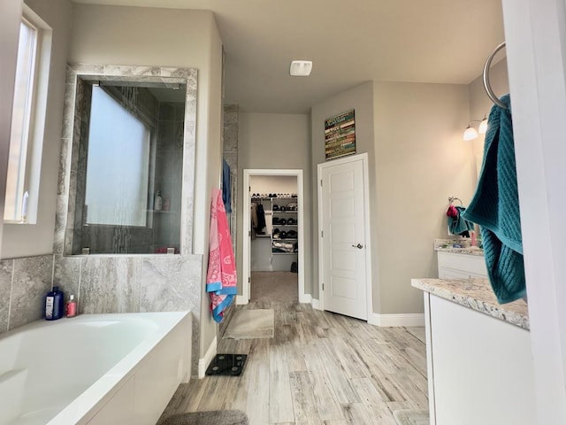 full bath with vanity, baseboards, wood finished floors, a spacious closet, and a bath