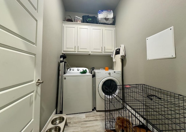 laundry room featuring light wood finished floors, cabinet space, and washing machine and dryer
