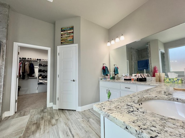 full bathroom featuring double vanity, a stall shower, and wood finished floors