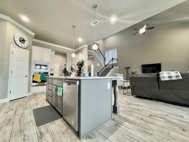 kitchen with ceiling fan, light wood-style floors, stainless steel appliances, decorative light fixtures, and white cabinetry