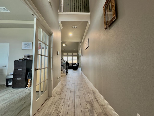 hallway with french doors, baseboards, wood finished floors, and visible vents