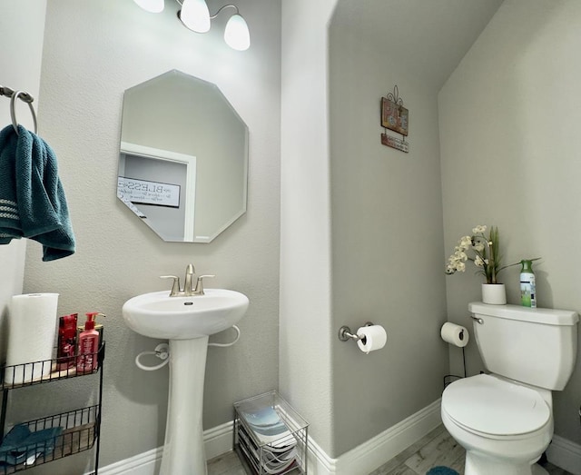 half bath featuring baseboards, a sink, and toilet