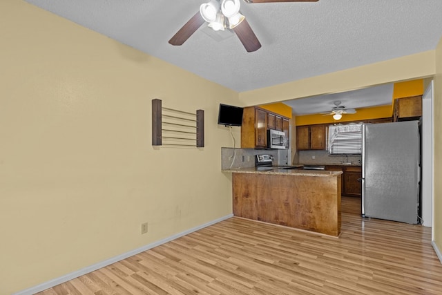 kitchen with decorative backsplash, light hardwood / wood-style floors, kitchen peninsula, stainless steel appliances, and a textured ceiling