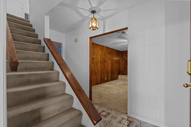 stairway featuring carpet floors and wood walls