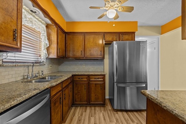 kitchen featuring appliances with stainless steel finishes, sink, light stone counters, and light hardwood / wood-style floors