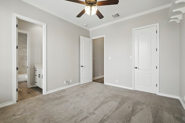 unfurnished bedroom with carpet, ornamental molding, connected bathroom, baseboards, and ceiling fan