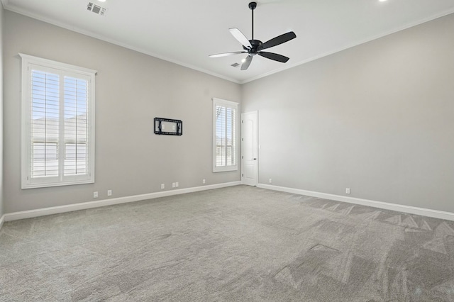 carpeted spare room featuring ornamental molding, baseboards, and ceiling fan