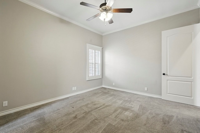 spare room featuring crown molding, carpet flooring, baseboards, and a ceiling fan