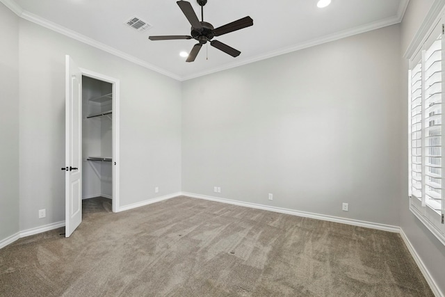 unfurnished bedroom featuring carpet, recessed lighting, a walk in closet, baseboards, and ornamental molding