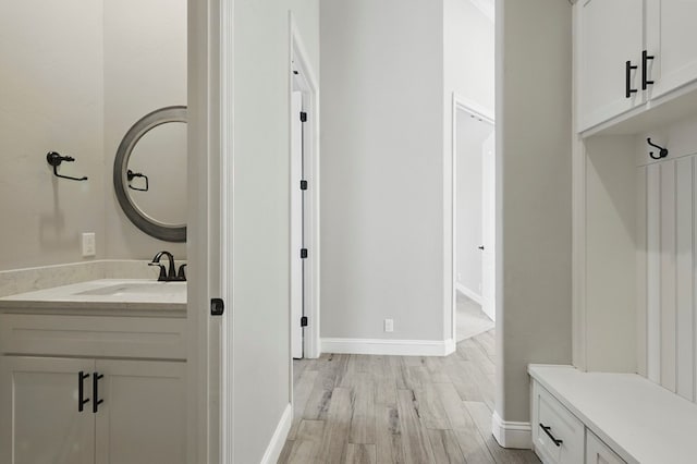 mudroom with a sink, light wood-type flooring, and baseboards