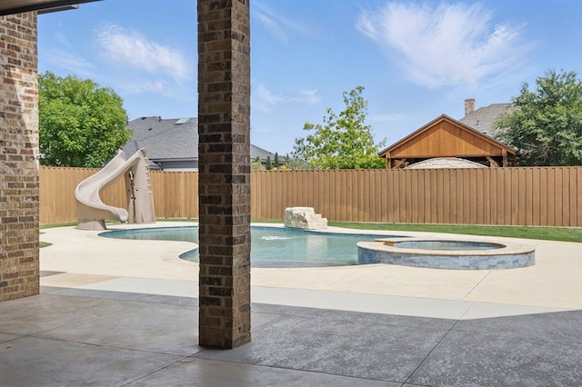 view of pool featuring a fenced backyard, a water slide, a patio area, and a pool with connected hot tub