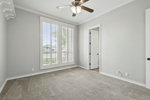 spare room featuring carpet flooring, baseboards, ceiling fan, and ornamental molding
