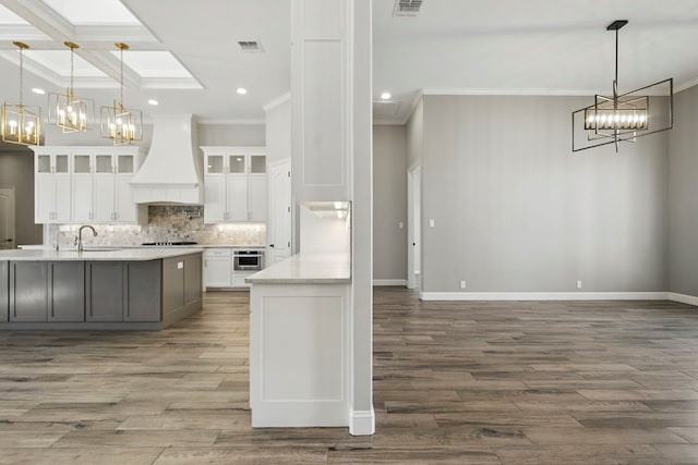 kitchen with custom range hood, a chandelier, recessed lighting, ornamental molding, and light countertops