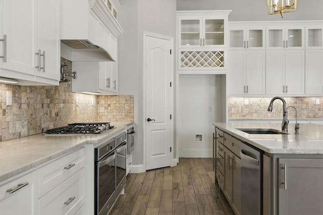 kitchen featuring a sink, appliances with stainless steel finishes, premium range hood, glass insert cabinets, and dark wood finished floors