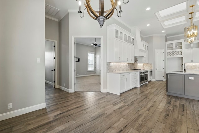 kitchen with a chandelier, a sink, crown molding, light countertops, and decorative backsplash