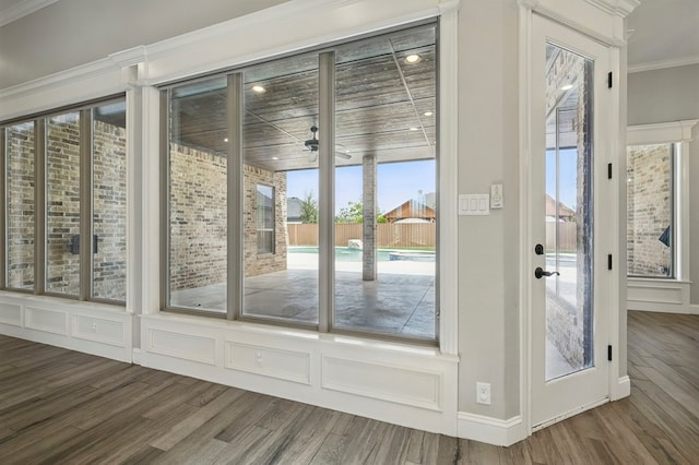doorway to outside featuring wood finished floors, crown molding, and ceiling fan