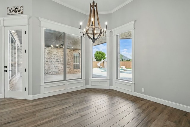 unfurnished dining area featuring wood finished floors, a chandelier, and crown molding