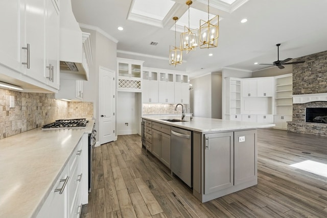 kitchen featuring stainless steel appliances, a sink, ornamental molding, ceiling fan, and dark wood-style flooring