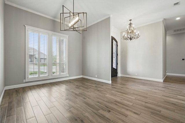 unfurnished dining area with a chandelier, baseboards, wood finished floors, ornamental molding, and arched walkways