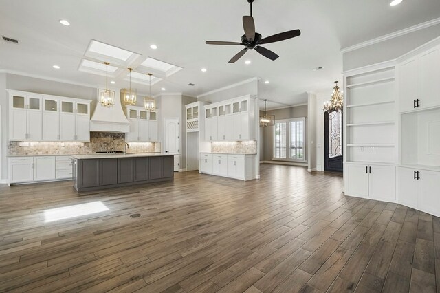 unfurnished living room with a chandelier, ornamental molding, ceiling fan, dark wood-type flooring, and recessed lighting