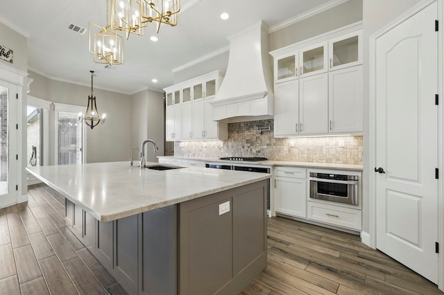 kitchen featuring a chandelier, stainless steel oven, custom exhaust hood, a sink, and recessed lighting