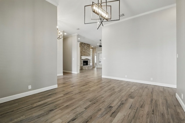 unfurnished living room with a chandelier, crown molding, baseboards, wood finished floors, and a fireplace