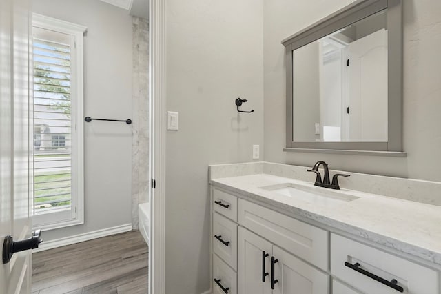 bathroom with vanity, wood finished floors, baseboards, and washtub / shower combination