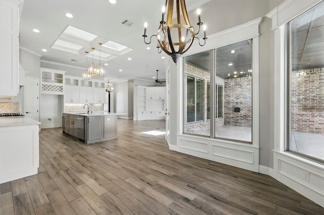 kitchen featuring a chandelier, stainless steel dishwasher, open floor plan, decorative backsplash, and white cabinetry