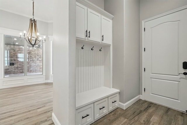 mudroom featuring light wood-style flooring, a chandelier, and ornamental molding
