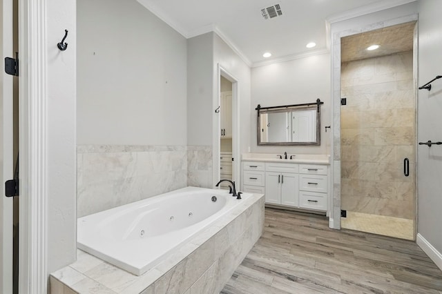 full bathroom with ornamental molding, a tub with jets, a stall shower, vanity, and wood finished floors