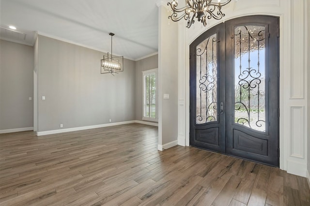 foyer featuring french doors, a chandelier, wood finished floors, and ornamental molding
