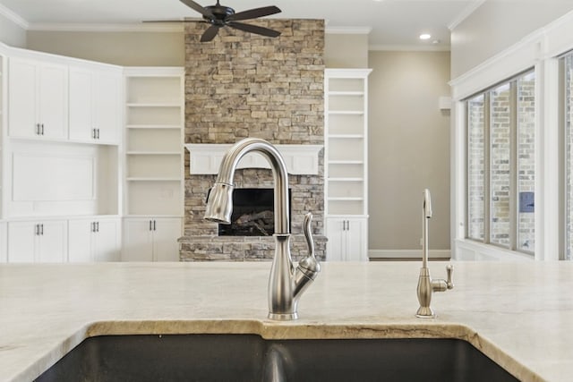 kitchen featuring ceiling fan, a sink, crown molding, recessed lighting, and a stone fireplace